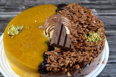 Dondurmalı pasta, üzerinde çikolata parçacıkları ve krema ve sos ile kaplı, fıstıklı çikolata parçaları, yarım mango ve yarım çikolata, yaz ve tatil konsepti.