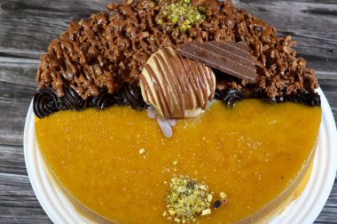 Dondurmalı pasta, üzerinde çikolata parçacıkları ve krema ve sos ile kaplı, fıstıklı çikolata parçaları, yarım mango ve yarım çikolata, yaz ve tatil konsepti.