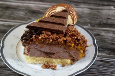 Dondurma topu ve gofret bir parça dondurmanın üzerinde, üzerinde çikolata parçaları, krema ve sos, üzerinde şam fıstığı, yarım mango ve yarım çikolata olan bir kek tabakası.