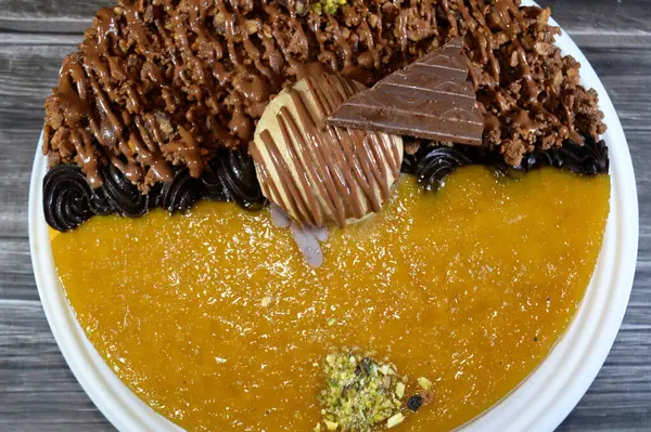 Dondurmalı pasta, üzerinde çikolata parçacıkları ve krema ve sos ile kaplı, fıstıklı çikolata parçaları, yarım mango ve yarım çikolata, yaz ve tatil konsepti.