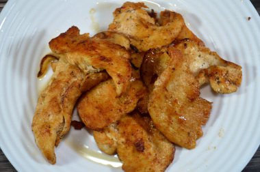 Tavada kızartılmış tavuk göğsü fileto soğan, kekik, paprika ve tuz dilimleri, bir tabakta pişirilmiş tavuk parçaları.