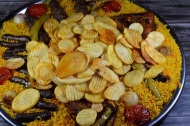 Bir tepsi çeşit çeşit ızgara kömür ızgara ızgara biftek kıymalı et kufta, sosis, ızgara tavuk, kızarmış patates cipsi, yeşil biber, domates, soğan ve sarı Hint Basmati pilavı.