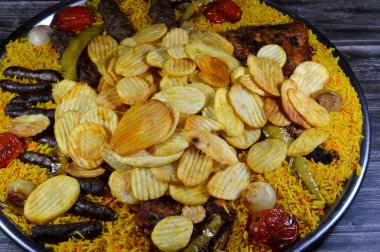 Bir tepsi çeşit çeşit ızgara kömür ızgara ızgara biftek kıymalı et kufta, sosis, ızgara tavuk, kızarmış patates cipsi, yeşil biber, domates, soğan ve sarı Hint Basmati pilavı.