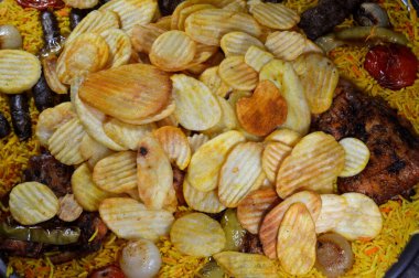 Bir tepsi çeşit çeşit ızgara kömür ızgara ızgara biftek kıymalı et kufta, sosis, ızgara tavuk, kızarmış patates cipsi, yeşil biber, domates, soğan ve sarı Hint Basmati pilavı.