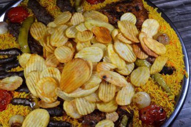 Bir tepsi çeşit çeşit ızgara kömür ızgara ızgara biftek kıymalı et kufta, sosis, ızgara tavuk, kızarmış patates cipsi, yeşil biber, domates, soğan ve sarı Hint Basmati pilavı.