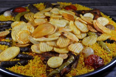 Bir tepsi çeşit çeşit ızgara kömür ızgara ızgara biftek kıymalı et kufta, sosis, ızgara tavuk, kızarmış patates cipsi, yeşil biber, domates, soğan ve sarı Hint Basmati pilavı.