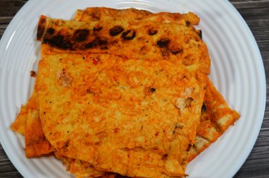 Katlanmış ince tortilla ekmeği bir tavada, ince, dairesel mayasız bir ekmek, masadan yapılmış ve buğday unundan yapılmış, pita düz ekmek tostu, öğünlerin yanında atıştırmalık olarak servis ediliyor.