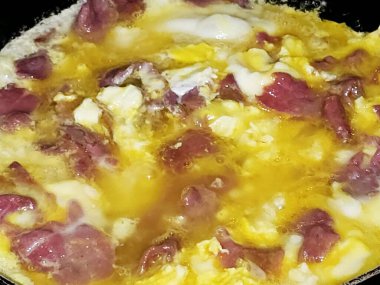 Scrambled eggs with pastrami, a dish made from eggs stirred, whipped or beaten together while being gently heated, with salt, butter, oil and black pepper with slices and pieces of beef pastrami