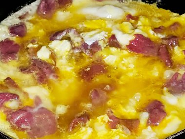 Scrambled eggs with pastrami, a dish made from eggs stirred, whipped or beaten together while being gently heated, with salt, butter, oil and black pepper with slices and pieces of beef pastrami