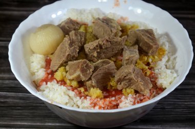 Tipik olarak, bir taban pişmiş beyaz pirinç, haşlanmış et parçaları, kızarmış ekmek, domates sosu ve sarımsak, genellikle ziyafette yenen Mısır yemeği,