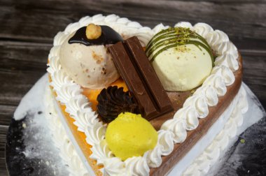 Dondurma, çeşitli aromalı ve içinde kek katmanı olan dondurmalı pasta, dondurma, mango, vanilya ve çikolata, şam fıstığı topu ve sos ve fındık topu.