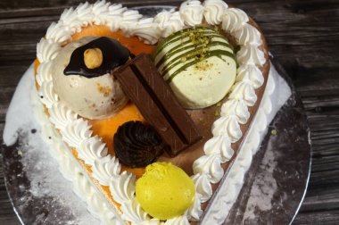 Dondurma, çeşitli aromalı ve içinde kek katmanı olan dondurmalı pasta, dondurma, mango, vanilya ve çikolata, şam fıstığı topu ve sos ve fındık topu.