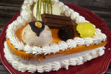 Dondurma, çeşitli aromalı ve içinde kek katmanı olan dondurmalı pasta, dondurma, mango, vanilya ve çikolata, şam fıstığı topu ve sos ve fındık topu.