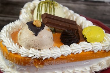 Dondurma, çeşitli aromalı ve içinde kek katmanı olan dondurmalı pasta, dondurma, mango, vanilya ve çikolata, şam fıstığı topu ve sos ve fındık topu.