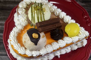 Dondurma, çeşitli aromalı ve içinde kek katmanı olan dondurmalı pasta, dondurma, mango, vanilya ve çikolata, şam fıstığı topu ve sos ve fındık topu.