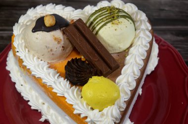 Dondurma, çeşitli aromalı ve içinde kek katmanı olan dondurmalı pasta, dondurma, mango, vanilya ve çikolata, şam fıstığı topu ve sos ve fındık topu.