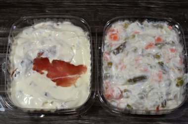 Rus salatasının arka planı, Olivier salatası, kremalı mayonez ve kremalı bezelye kaplı patatesler, havuçlar ve sığır etinden yapılmış ince dilimlenmiş pastırma dilimleriyle kaplı kremalı peynir.