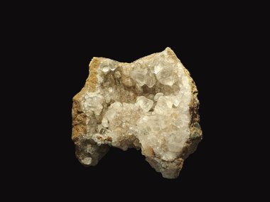 Kaba, kahverengimsi dış görünüşü koyu bir arka planda sergilenen beyaz kristallere sahip kalsit jeotunun yakın görüntüsü