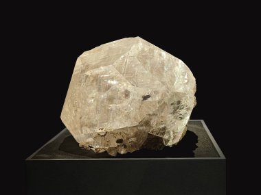 A close-up view of a large, transparent to translucent calcite crystal with a slightly yellowish hue displayed on a dark background clipart