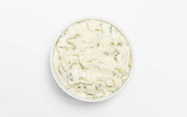 İzole edilmiş geleneksel Yunan yoğurt sosu Tzatziki, beyaz kâseye sarımsak, rendelenmiş salatalık, ekşi kremalı yoğurt, zeytinyağı, sarımsak, beyaz arka planda bitkiler. Yaklaş, düz yat, yatay