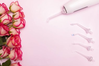 Uluslararası Diş Hekimleri Günü 'nüz kutlu olsun gül çiçekleri, diş temizleyicisi, pembe arka planda diş fırçası. Profesyonel tatil için diş sağlığı tebrik kartı. Odaklanma alanı, merkezde metin için yatay düzlem alanı