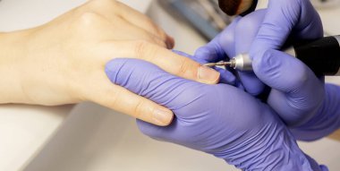 Eldivendeki kesilmiş tırnak teknisyenleri müşterileri tırnak altlarını hırdavat makinesiyle söker, tırnak fırçası tutarlar. Manikür, güzellik tırnak bakımı, kaplıca salonu. Yatay düzlem