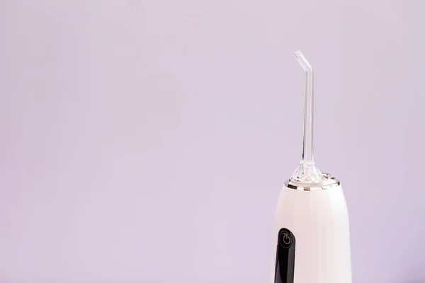 クロップドオーラルティース灌漑 歯科用水歯クリーナー 紫の背景に白いポータブル充電式コードレス水歯科用花 ノズル付き防水ホーム歯科ケアデバイス — ストック写真
