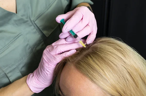 Trichologist, beautician doing blond woman hair mesotherapy procedure. White doctor does scalp injections with syringe. Bio stimulation, hair cells treatment, hair loss,alopecia prevention. Horizontal