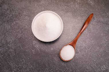 Organik tatlandırıcı eritritol, mısır fermantasyonundan üretilen, seramik kasede dekstroz, granit zemin üzerinde tahta kaşık, masa. Şekerin yerine. Yatay düzlem, üst görünüm, boşluğu kopyala.