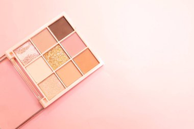 Gözler için çok renkli palet kozmetik, pembe arka planda yüz. Minimalizm makyajı, hassas gölgeler. Uzayı sağ tarafta, yatay düzlemde, düzlükte metin için kopyalayın. Yüksek kalite fotoğraf