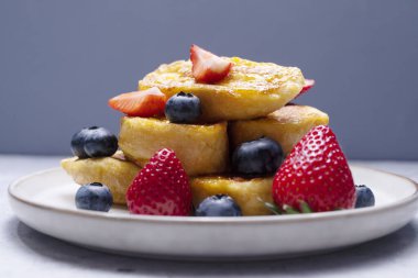 Yakın çekim Torrijas, dilimlenmiş Brioche, Ekmek, Portakal Toplama, Glaze, taze yabanmersini, Çilekli Tabak, Granit Masa. Kahvaltıda Lezzetli Tatlı. Yatay düzlem.