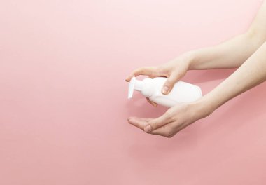 Kadın Elleri Pembe Arkaplandaki Plastik Tüpten Boş Beyaz Şişe Basına Basıyor. Hijyen, Kozmetik Güzellik Ürünleri, Yıkama, Temizleme Özel Jeli, Köpük. Günlük Vücut Bakımı. Yatay, Kopyalama.
