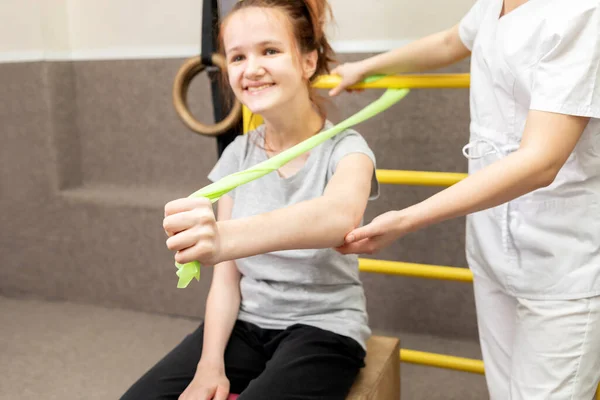Engelli Mutlu Çocuk, rehabilitasyon odasındaki doktorun desteğiyle fiziksel egzersiz yapıyor. Özel ihtiyaçları olan çocuk. Rehabilitasyon. Beyin felci geçirmiş. Motor Bozukluk. Yatay düzlem