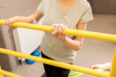 Doktorla birlikte engelli bir genç kız rehabilitasyon odasında fiziksel egzersiz yapıyor. Özel ihtiyaçları olan çocuk. Rehabilitasyon. Beyin felci geçirmiş. Motor Bozukluk. Yatay düzlem. Yüksek kalite fotoğraf.