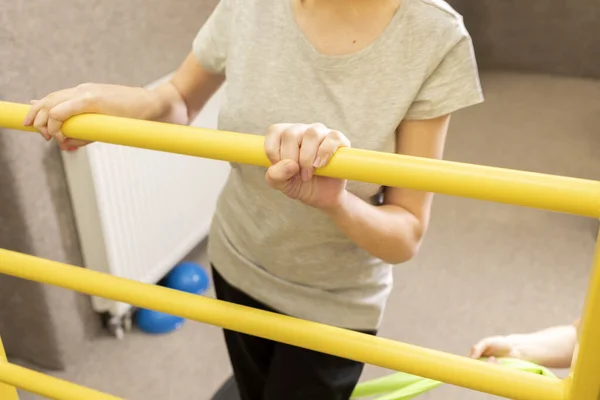 Doktorla birlikte engelli bir genç kız rehabilitasyon odasında fiziksel egzersiz yapıyor. Özel ihtiyaçları olan çocuk. Rehabilitasyon. Beyin felci geçirmiş. Motor Bozukluk. Yatay düzlem. Yüksek kalite fotoğraf.