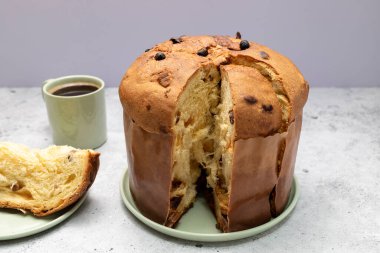 Panettone İtalyan tatlı keki, bir parça kes ve masaya bir fincan kahve koy ve bir parça kes. Tatlı ekmek, aslen İtalyan olan Meyveli Kek, Milan Fırınlanmış Tatlı. - Yakın çekim. Yatay düzlem. Yüksek kalite fotoğraf