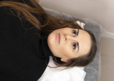 Kalıcı makyajı olan güzel bir kadın güzellik salonunda kaşlarını yaptırıyor, koltukta uzanıyor. Kozmetik Prosedür. İyileştirilmiş Kaşlar. Uzun ömürlü yolcu gemisi. Deri mikro pigmentasyonu. Yatay Düzlem. 