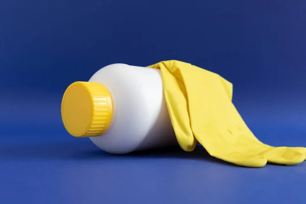 Pipe Unclogging Granules In Yellow Cap, White Plastic Bottle, Rubber Glove On Blue Purple Background. Super Drain Cleaner, Housework Help. Horizontal Plane, Closeup. High quality photo