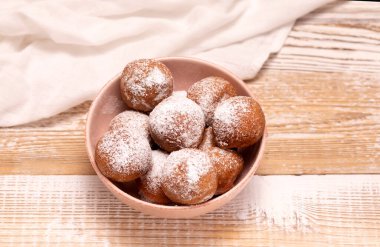 Paczki ya da Zeppole in Pembe Bowl. Tahta masadaki pudra şekerli. Şişman Perşembe Karnavalı ya da Tlusty Czwartek, Hıristiyan Donut Yeme geleneği, Lezzetli Çörekler. Yatay Düzlem