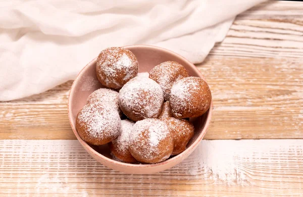 Flatly Paczki Or Zeppole In Pink Bowl With Powdered Sugar On Wooden Table. Fat Thursday Carnival or Tlusty Czwartek, Christian tradition Of Eating Doughnut, Delicious Donuts. Horizontal Plane