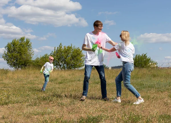 stock image Caucasian Family Plays With Colorful Dye At Birthday Party Or Celebrates Holi Color Festival, Throwing Multicolor Powder. Cheerful Parent, Child Plays With Paint Outdoor In Park. Horizontal Plane.