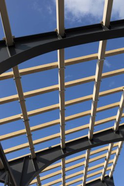 Baraka, çatı inşaatı, tahtalardan ahşap bir kubbe yapma süreci ve yapısal çelik kiriş, insan yok. Arkadaki Mavi Gökyüzü. Mühendislik. Dikey Düzlem,