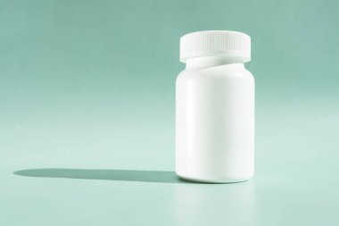 Beyaz ilaç şişesi ya da yeşil ya da turkuazlı vitaminler, gölgeli nane arkaplanı. Yatay düzlem. Metin için Boşluğu Kopyala. Sağlıklı Biyolojik İlaveler. Eczacılık. Tasarım veya Model.