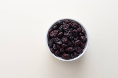 Bej arka planda beyaz kasede kurutulmuş kızılcık yığını. Uzayı kopyala Tatlı susuz kızılcık. Besinler ve vitaminler. Yatay Düzlem