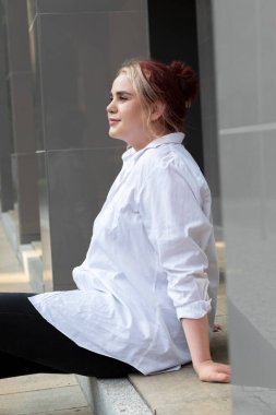 Profile göre 20 'li yaşlarda güzel bir kadın, öğrenci korkulukta oturuyor, merdivenler. Renkli saçlı, tasasız, güzel bir kız dışarıda eğleniyor. G jenerasyonu kadın günlük kıyafetler giyer. Dikey.