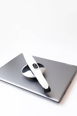 Bilgisayarda Dişleri Görüntülemek için 3D Tarayıcı, Not Defteri. Masanın üzerinde yatan beyaz 3d Dişçiler arası Tarayıcı. Diş teçhizatı, dişleri taramak için aygıt. Diş hekimliği. Dikey Düzlem.