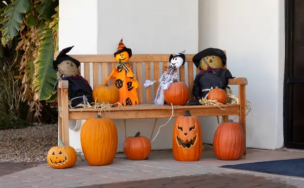 Creepy Pumpkins with Faces, Scary Scarecrows on Bench Are Traditional Halloween Decor. Outdoor Spooky Decoration For Halloween Party. Horizontal Plane High quality photo