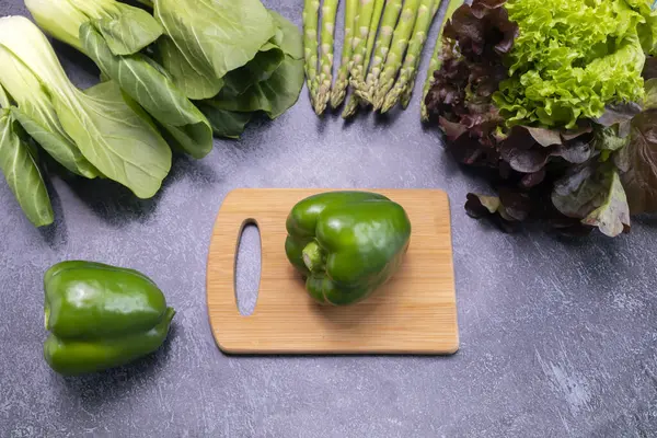 Top View Assortment Of Fresh Organic Vegetables, Green Bell Pepper On Cutting Board On Table. Asparagus Plant, Bok Choy, Red Leaf Lettuce. Healthy Bio Food, Longevity Diet. Horizontal Plane. Flatly
