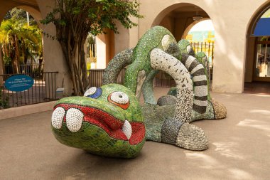 Colorful Mosaic animal Sculpture Dragon Nikigator Near Mingei Museum, Balboa Park Created By French American Sculptor Niki De Saint Phalle. Horizontal. San Diego, Usa. March 13, 2024  clipart