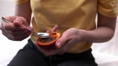 Kişi, Taze Tamarillo Yiyen Kadın, Kaşıklı Taze Tropik Egzotik Meyve. Yumurta şeklinde yenilebilir meyve, Ağaç Domatesleri olarak bilinir, Bitki Ailesi Solanaceae, Solanum Betaceum. Ağır çekim. Yatay Kapatma.